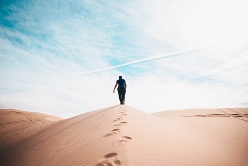 足跡を残して砂漠を進み続ける男性