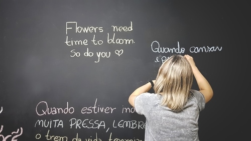 黒板にさまざまな言語で文字を書く女性